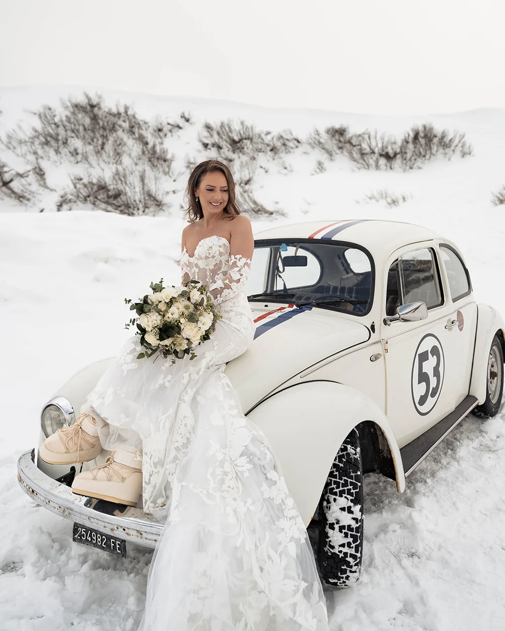 Bride sitting on a classic car in the snow