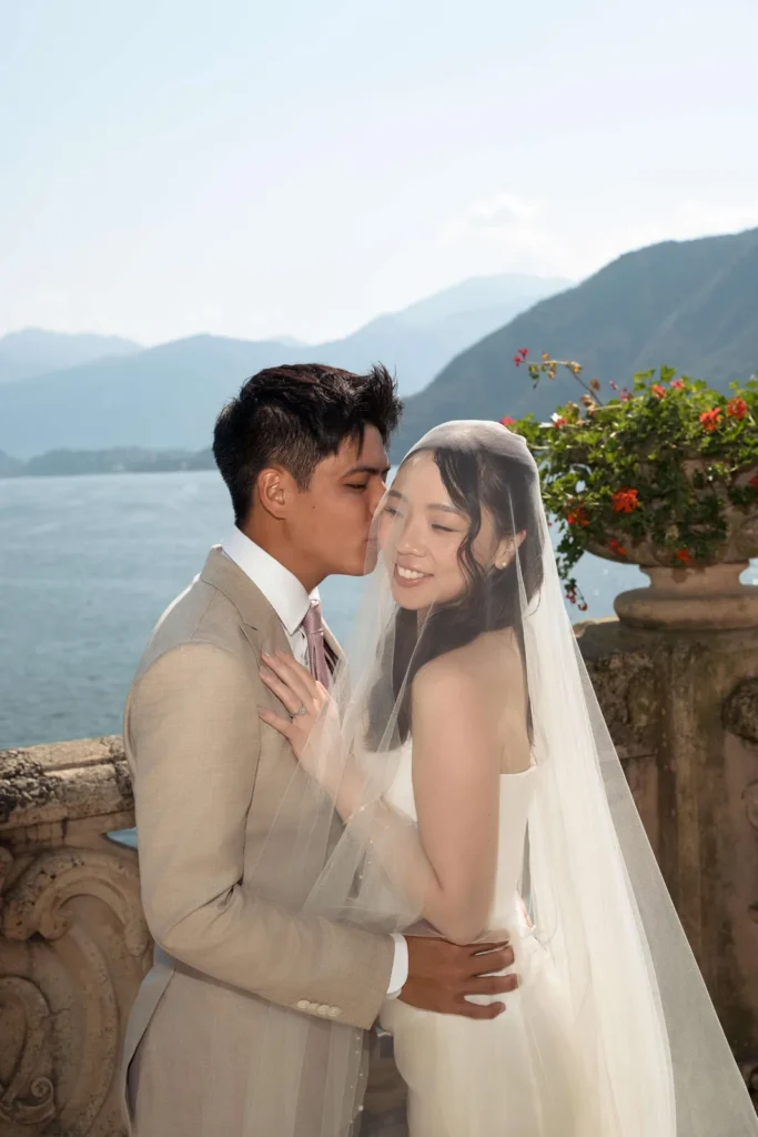 Groom kissing the bride on a terrace above Lake Como