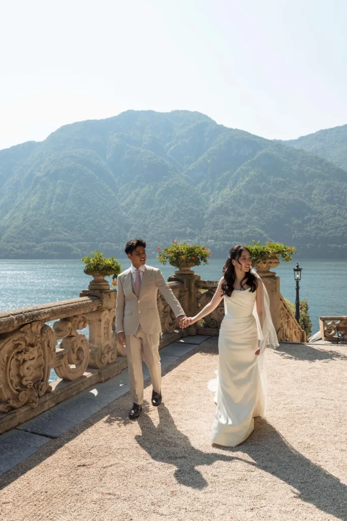 Newlyweds walking along a balustraded terrace on Lake Como