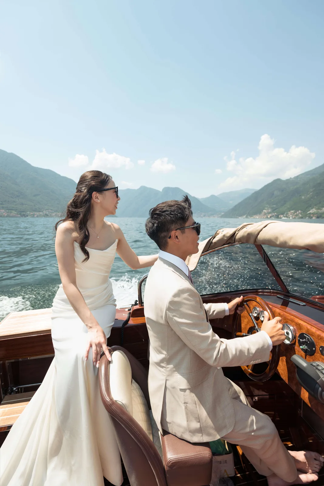 Groom driving a wooden motorboat across Lake Como with the bride