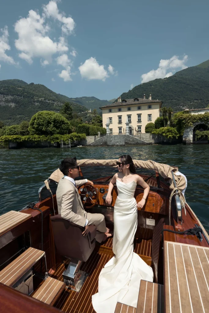 Bride on a wooden motorboat in front of a lakeside villa