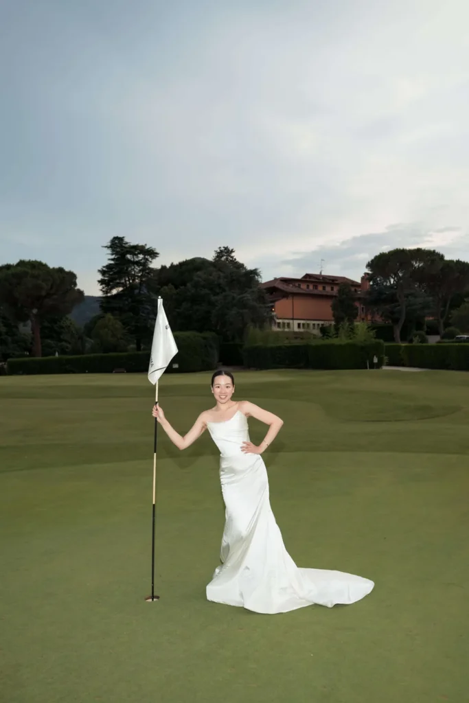 Bride in her wedding dress by the flag on a golf green near Padua
