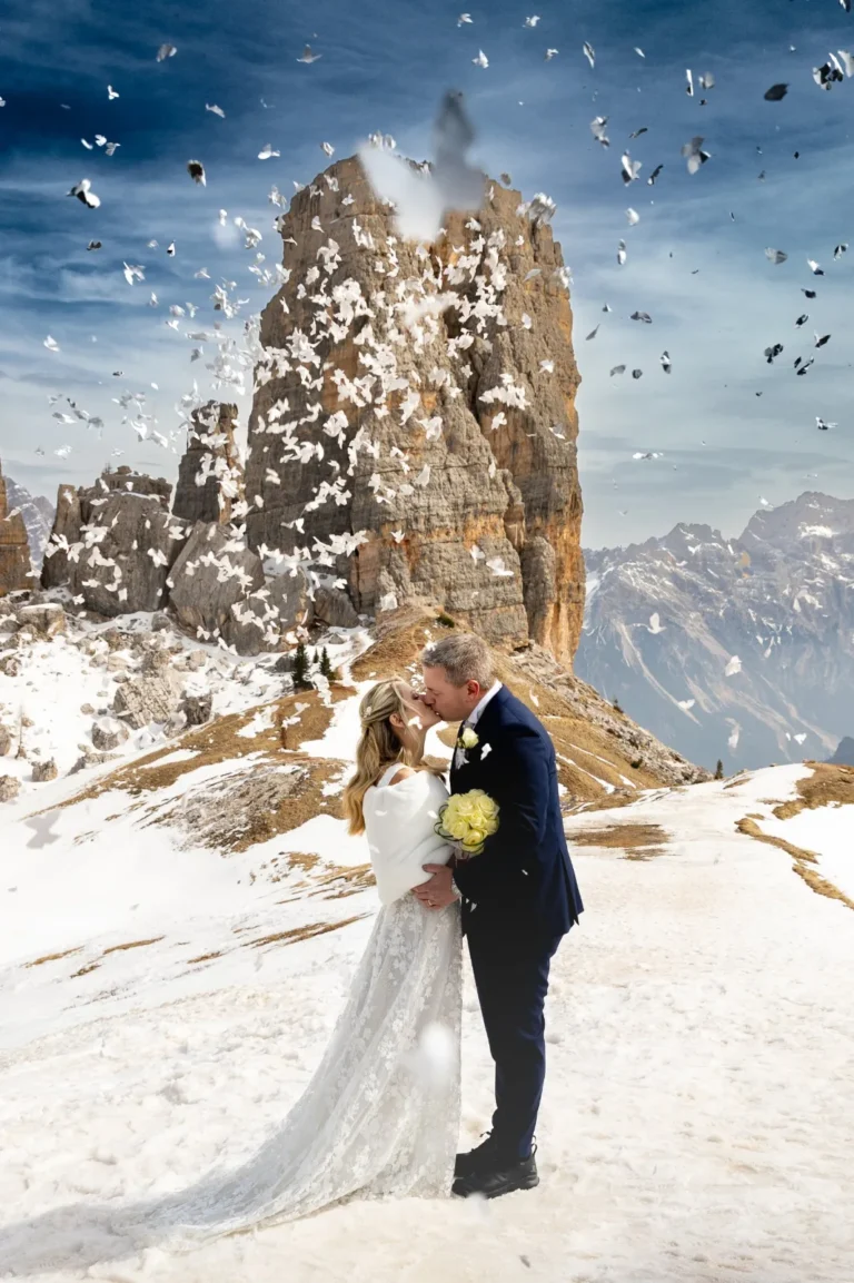 Martina and Stefano kissing under a shower of confetti at the Cinque Torri in the snow