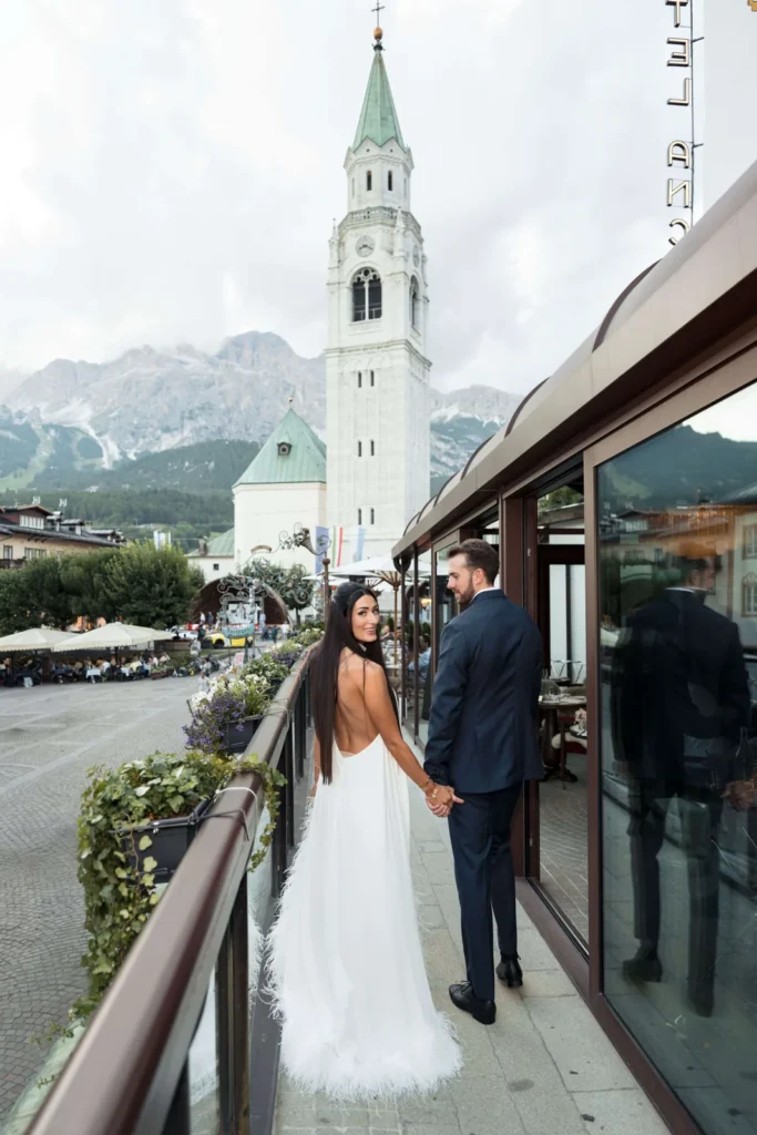 Mia and Boone on a terrace facing the Cortina bell tower and the Dolomites