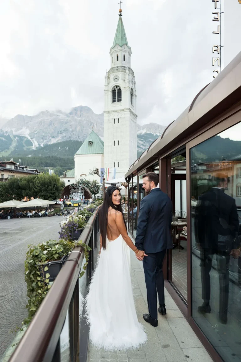 Mia and Boone on a terrace facing the Cortina bell tower and the Dolomites