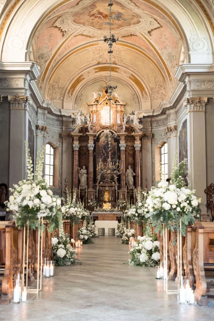 Aisle of the Cortina basilica lined with white flowers and candles