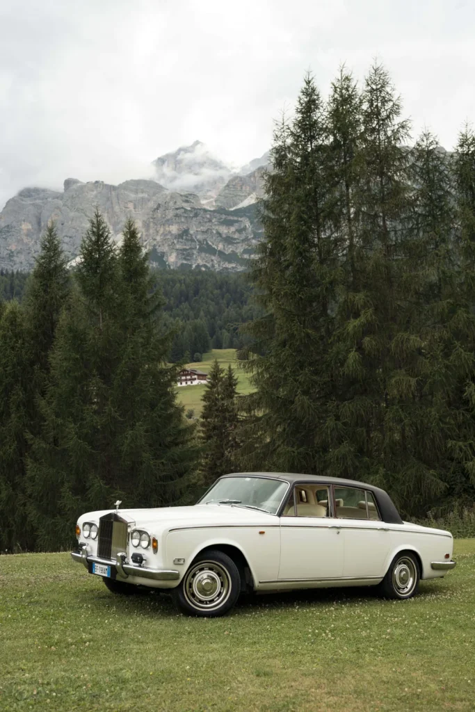 Classic white car in a meadow beneath the Dolomites