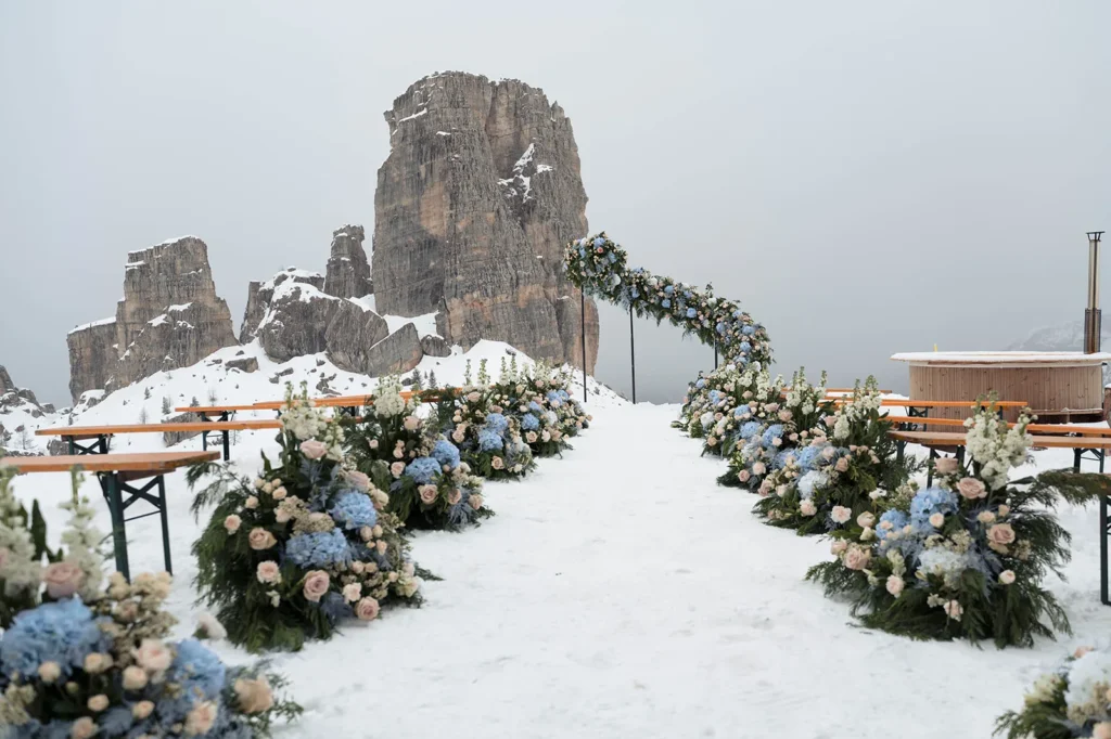 Snowy aisle lined with blue and white flowers at the Cinque Torri