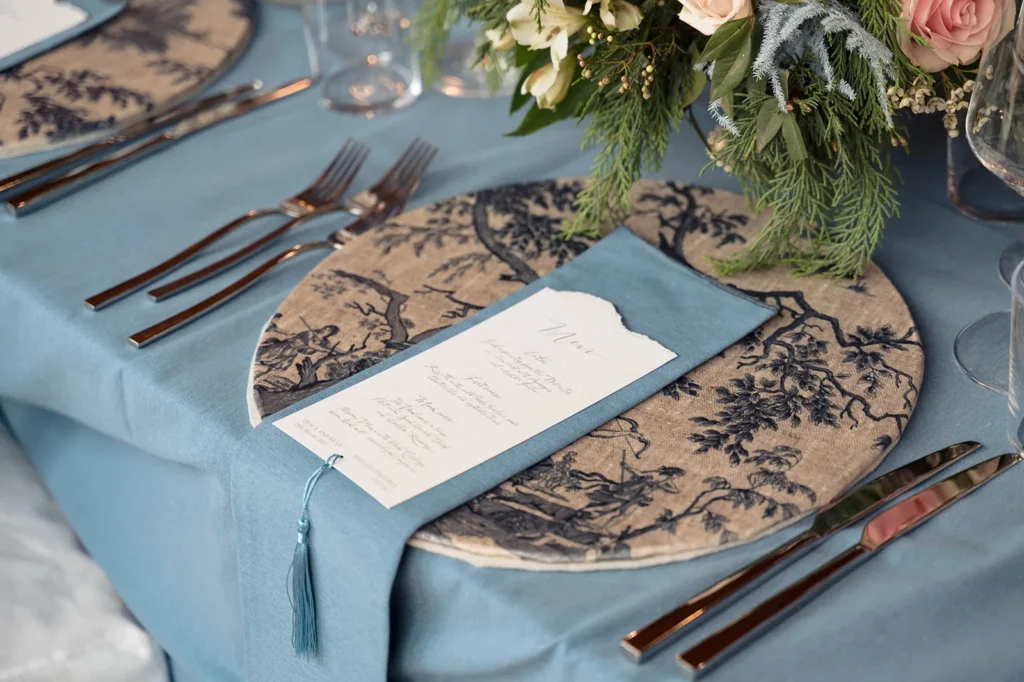 Wedding dinner table with blue linen and toile plates